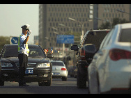 A traffic policeman works under sun as a driver tries to present him a bottle of mineral water on street in Beijing, capital of China, July 5, 2010. Chinese meteorological authority said Monday hot weather continues to scorch many parts of the country.[Xinhua]