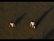 Two men swim at Yong River in Nanning, capital of southwest China's Guangxi Zhuang Autonomous Region, July 5, 2010. Chinese meteorological authority said Monday hot weather continues to scorch many parts of the country. The highest temperature of Guangxi reached 39.5 degrees Celsius on Monday.[Xinhua]