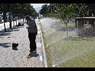 An old man walks with his pet dog on street in Beijing, capital of China, July 5, 2010. Chinese meteorological authority said Monday hot weather continues to scorch many parts of the country. [Xinhua]