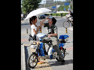 A young man cools himself with a bottle of iced mineral water on his head on street in Beijing, capital of China, July 5, 2010. Chinese meteorological authority said Monday hot weather continues to scorch many parts of the country. [Xinhua]