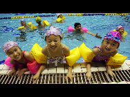 Children take part in swimming training to enjoy coolness at the indoor pool of Shandong Sports Center in Jinan, capital of east China's Shandong Province, July 5, 2010.  [Xinhua]
