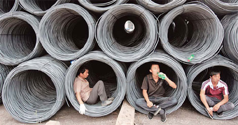 Workers take a break inside steel coils at Taiyuan Steel Market in Shanxi province. China is encouraging big steel mills to merge with rivals. [China Daily]