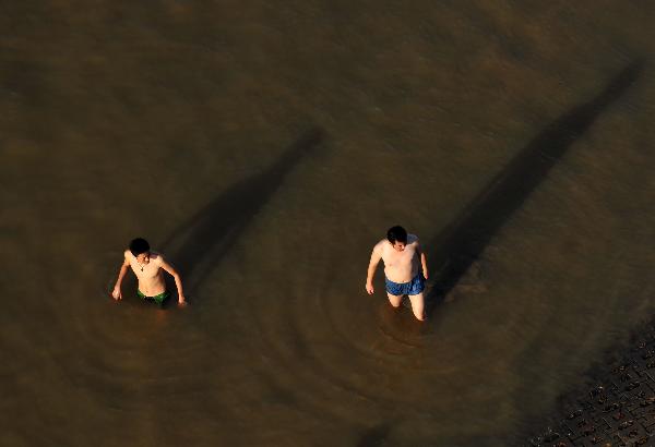 Two men swim at Yong River in Nanning, capital of southwest China's Guangxi Zhuang Autonomous Region, July 5, 2010. Chinese meteorological authority said Monday hot weather continues to scorch many parts of the country. The highest temperature of Guangxi reached 39.5 degrees Celsius on Monday.
