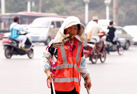 A street cleaner is soaked in perspiration on Tuesday in Zhengzhou, capital of Henan province, where the mercury hit 38 C. 
