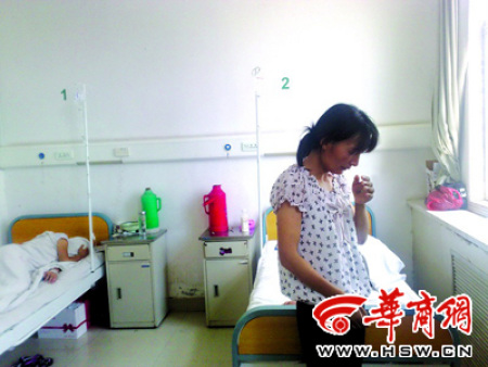 A mother cries in a hospital as a child in the background hides her face.