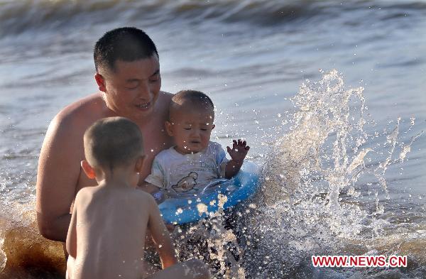 Citizens play at seaside of the Xixiu Beach in Haikou, capital of south China's Hainan Province, July 6, 2010. The local meteorologic authority has continuously issued alarms against high temperature recently. 
