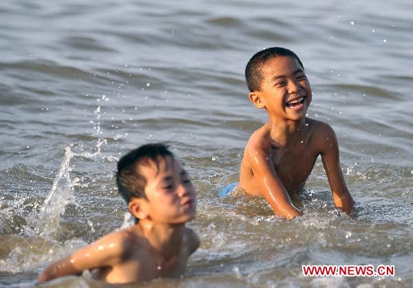 Children play in the sea at the Xixiu Beach in Haikou, capital of south China's Hainan Province, July 6, 2010. The local meteorologic authority has continuously issued alarms against high temperature recently. 