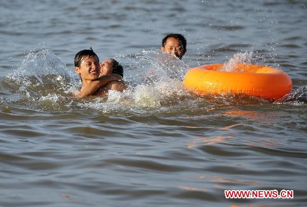 Children play in the sea at the Xixiu Beach in Haikou, capital of south China's Hainan Province, July 6, 2010. The local meteorologic authority has continuously issued alarms against high temperature recently. 