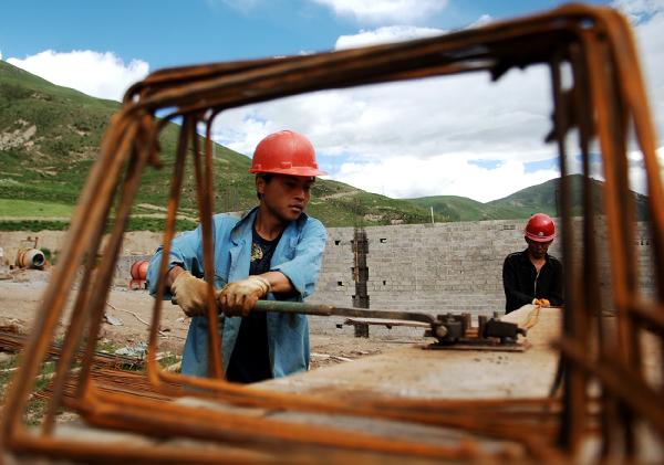 Workers work at a construction site at Changu Village of quake-hit Yushu in northwest China's Qinghai Province, July 6, 2010. The reconstruction work is underway in Changu Village and a total of 206 permanent houses will be finished on August 20, according to the reconstruction plan. 