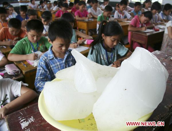 Ice cubes are placed in a classroom to ease the heat, where pupils are taking their terminal examination, at the Central Primary School of Tancheng Town in Tancheng County, east China&apos;s Shandong Province, July 7, 2010. [Xinhua]
