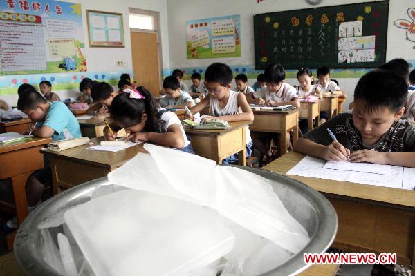 Ice cubes are placed in a classroom to ease the heat, where pupils are taking their terminal examination, at the Central Primary School of Tancheng Town in Tancheng County, east China&apos;s Shandong Province, July 7, 2010. [Xinhua]