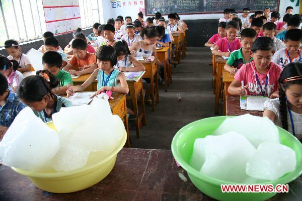  Ice cubes are placed in a classroom to ease the heat, where pupils are taking their terminal examination, at the Central Primary School of Tancheng Town in Tancheng County, east China&apos;s Shandong Province, July 7, 2010. [Xinhua] 