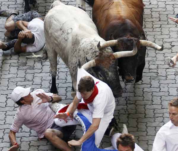 A Penajara fighting bull grabs a runner by the shirt on the first day of the running of the bulls during the San Fermin festival in Pamplona July 7, 2010. Six bulls are released every morning at 8:00 through the cobbled streets of Pamplona to the bullring, where they will be killed in a bullfight in the afternoon.[Xinhua]