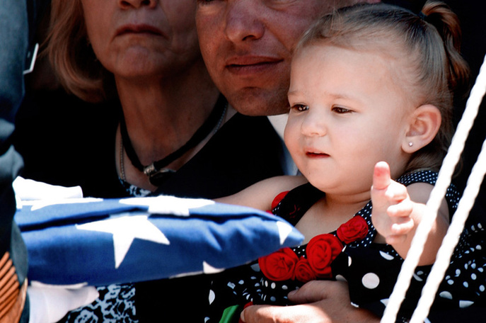 Two-year-old Faith Marie Adams reaches for one of the U.S. flags from her father, Army Spc. Christian M. Adams&apos; coffin, during military honors ceremonies at the Main Post Chapel on Fort Huachuca, Arizona on Tuesday, June, 22, 2010. Christian Adams, stationed at Fort Hood, Texas, died in Afghanistan on June 11. [yeeyan.org]