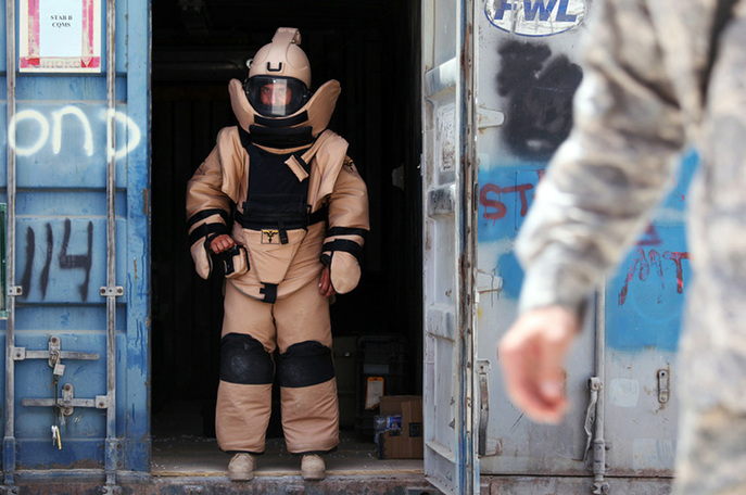 A member of a US Army Explosive Ordnance Disposal (EOD) team stands at the entrance to a container wearing a bomb disposal suit prior to an exercise at Camp Nathan Smith in Kandahar City on June 15, 2010. [yeeyan.org]