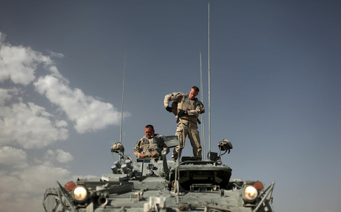 Members of the Royal Canadian Regiment stand on a Light Armored Vehicle (LAV) as they put on body armour at Camp Nathan Smith on June 16, 2010, prior to a patrol in Kandahar. [yeeyan.org]