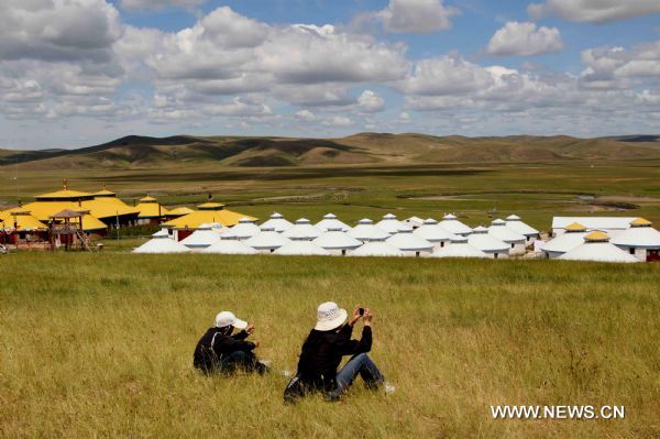 Tourists take photos in the Hulunbuir grassland of north China's Inner Mongolia Autonomous Region, July 6, 2010. The grassland entered the high tourist season recently.[Xinhua/Wang Yongji]