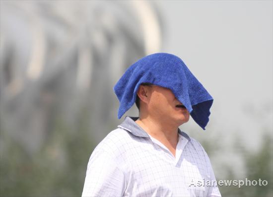 A man covers his head with a wet towel to shield himself from the sun in the Beijing Olympic Park on July 4, 2010. [China Daily/Asianewsphoto]