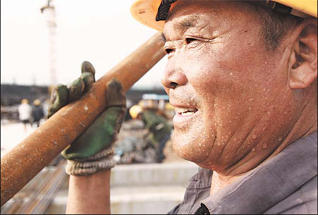 A worker carries building material on a construction site on Tuesday in Nanyang, Henan province, where the temperature reached 40 C.