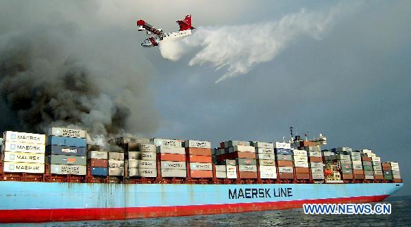 A plane sprays water on Charlotte Maersk, a Dutch cargo ship which caught fire en route from Malaysia&apos;s Port Klang to Oman on July 7, 2010. No casualties or injuries are reported thus far. [Xinhua]