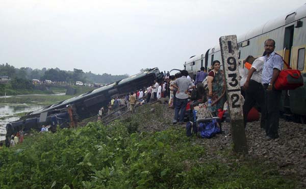 Passengers and railway officials stand beside derailed carriages of a passenger train after an explosion in Kokrajhar, in the northeastern Indian state of Assam, July 8, 2010. A powerful explosion on a railway track derailed a packed passenger train killing a five-year old boy and wounded seven others early Thursday in tea and oil rich northeastern Assam state, railway and police officials said. [Xinhua]