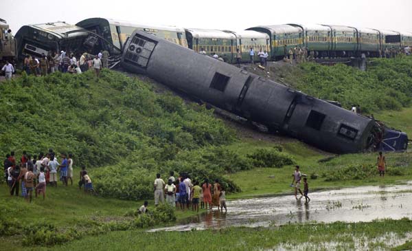 Onlookers and railway officials stand beside derailed carriages of a passenger train after an explosion in Kokrajhar, in the northeastern Indian state of Assam, July 8, 2010. [Xinhua]