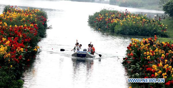 Excursionists revel in boating along the flowery brooklet on the upper reaches of Baihe River, with over 800,000 square meters of flowers and plants growing on the water surface that have remarkably beautified the ecological ambience and made it an tourist attraction in Shuangliu County, southwest China's Sichuan Province, July 7, 2010. [Xinhua]