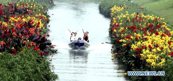 Excursionists revel in boating along the flowery brooklet on the upper reaches of Baihe River, with over 800,000 square meters of flowers and plants growing on the water surface that have remarkably beautified the ecological ambience and made it an tourist attraction in Shuangliu County, southwest China's Sichuan Province, July 7, 2010. (Xinhua) 