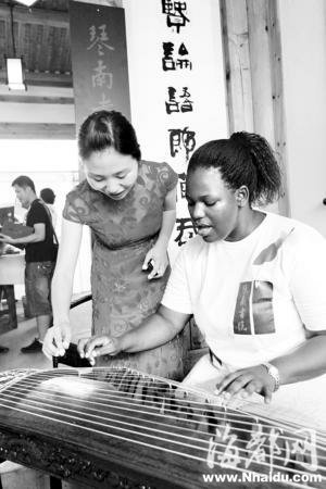 A Chinese lady teaches an African student to play guzheng, a traditional Chinese musical instrument, in an art school in Fuzhou, southeast China's Fujian Province, on July 6, 2010.