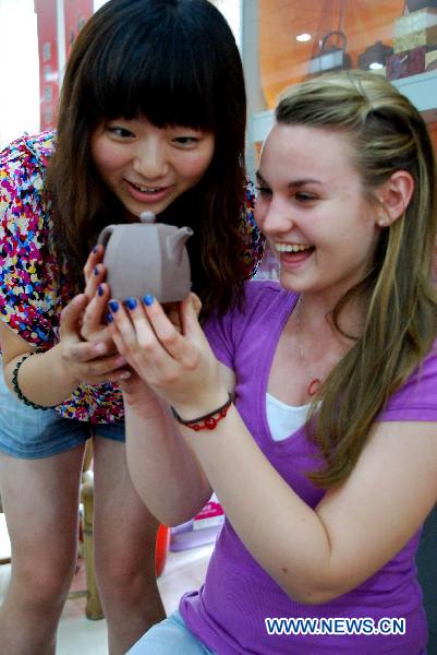 A high school student (R) from Arizona of the United States overjoys herself at fondling her own hand-made boccaro teapot at the Ceramics Town of Yixing City, east China's Jiangsu Province, July 8, 2010. Yixing city, enjoying the fame as 'ceramics capital', has been one of China's major ceramics producers for 2,000 years.