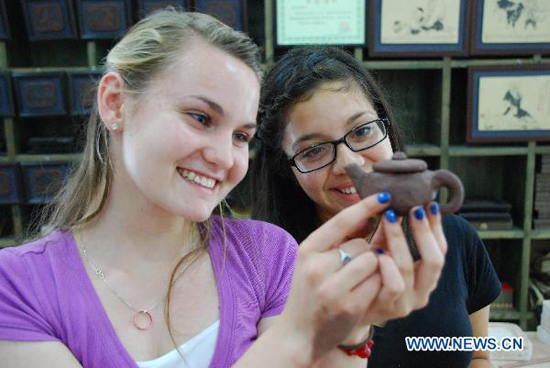 A high school student (L) from Arizona of the United States is joyous in showing up her own made boccaro teapot at the Ceramics Town of Yixing City, east China's Jiangsu Province, July 8, 2010. Yixing city, enjoying the fame as 'ceramics capital', has been one of China's major ceramics producers for 2,000 years.