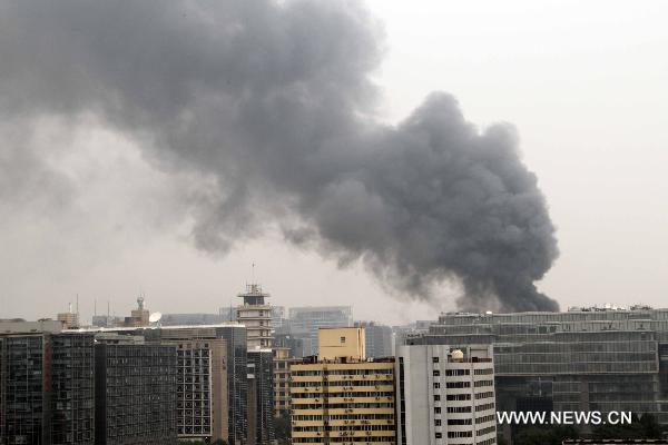 Smoke rises from a building that is on fire in the northeast corner of north Naoshikou street of Chang'an Avenue of Beijing, capital of China, July 9, 2010. (Xinhua/Gao Xueyu)