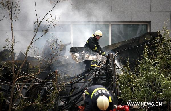 Firefighters try to put out a fire occurred in the northeast corner of north Naoshikou street of Chang'an Avenue of Beijing, capital of China, July 9, 2010