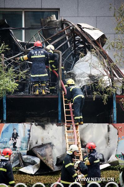 Firefighters try to put out a fire occurred in the northeast corner of north Naoshikou street of Chang'an Avenue of Beijing, capital of China, July 9, 2010.