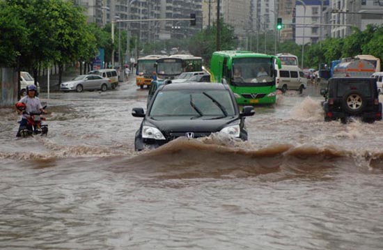 Vehicles drive in a flooded street after a heavy summer rain hit Southwest China's Chongqing municipality, July 9, 2010. The local meteorology bureau launched a level III emergency response after the heaviest rainfalls during this flood season hit downtown Chongqing and caused traffic congestion on Friday