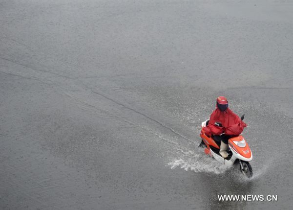 A citizen rides an electric bike on a rainy day in Hefei, capital of east China&apos;s Anhui Province, July 12, 2010. The provincial meteorological station raised the storm alert to &apos;orange&apos; Monday morning. China&apos;s Central Meteorological Station warned Sunday that rainstorms would again batter many provinces and regions in the coming days bringing with it bigger risks of new flooding and other geological disasters in central and eastern China. [Xinhua]