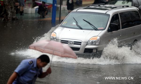 A car moves on a flooded street in Hefei, capital of east China&apos;s Anhui Province, July 12, 2010. The provincial meteorological station raised the storm alert to &apos;orange&apos; Monday morning. China&apos;s Central Meteorological Station warned Sunday that rainstorms would again batter many provinces and regions in the coming days bringing with it bigger risks of new flooding and other geological disasters in central and eastern China. [Xinhua]