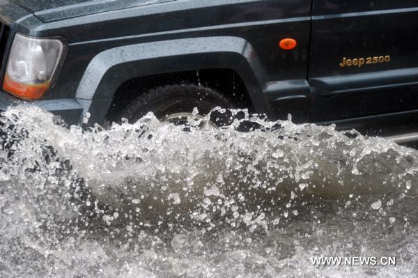 A car moves on a flooded street in Hefei, capital of east China&apos;s Anhui Province, July 12, 2010. The provincial meteorological station raised the storm alert to &apos;orange&apos; Monday morning. China&apos;s Central Meteorological Station warned Sunday that rainstorms would again batter many provinces and regions in the coming days bringing with it bigger risks of new flooding and other geological disasters in central and eastern China. [Xinhua]