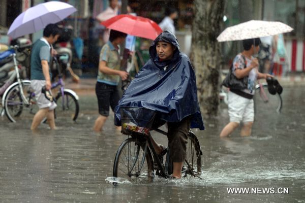 A citizen rides a bike on a rainy day in Hefei, capital of east China&apos;s Anhui Province, July 12, 2010. The provincial meteorological station raised the storm alert to &apos;orange&apos; Monday morning. China&apos;s Central Meteorological Station warned Sunday that rainstorms would again batter many provinces and regions in the coming days bringing with it bigger risks of new flooding and other geological disasters in central and eastern China. [Xinhua]