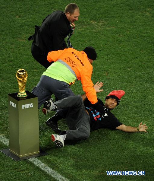 Security men knock down a fan (R) attempting to fetch the trophy before the World Cup final between the Netherlands and Spain at Soccer City stadium in Johannesburg, South Africa, July 11, 2010. [Xinhua]