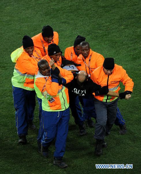 Security men catch a fan attempting to fetch the trophy before the World Cup final between the Netherlands and Spain at Soccer City stadium in Johannesburg, South Africa, July 11, 2010. [Xinhua]