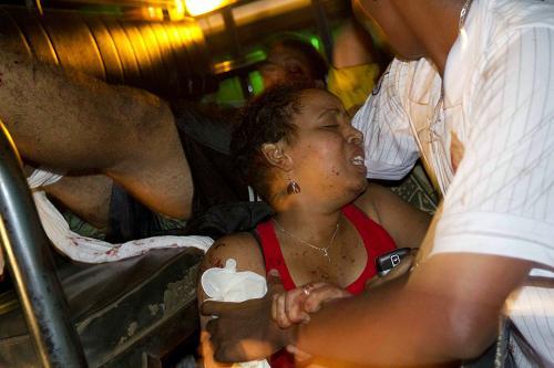 A man attends a injured women, Sunday, July 11, 2010, after a bomb went off in a restaurant in Kampala's Kabalagala district, named Ethiopian Village. [Xinhua photo]