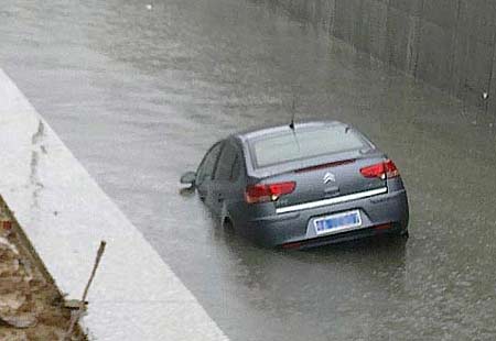 A car drives into a culvert filled with rainwater in Nanhu Park of downtown Wuhan, capital of Central China&apos;s Hubei province, July 11, 2010. The driver of the car succeeded in escaping just one minute before the car sunk. [xcar.com.cn]