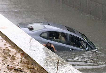 A man leaves his sinking car in the rainwater at Nanhu Park of downtown Wuhan, capital of Central China&apos;s Hubei province, July 11, 2010. [xcar.com.cn]