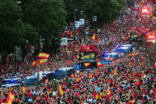 Crowds gather around Spain's national soccer team players as they celebrate on an open-top bus during a celebration parade in downtown Madrid, July 12, 2010. Spain stunned the Netherlands to win their first World Cup on Sunday in sensational fashion with a goal in the last minutes of extra time. (Xinhua/Reuters Photo)