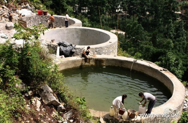 People build the water tanks in Jishan Village of Fengshan County, southwest China&apos;s Guangxi Zhuang Autonomous Region, July 12, 2010. The county planned to build more than 1,800 water tanks during the rainy season to fight against the dry season. [Xinhua] 