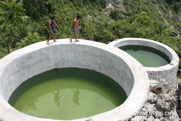 People check the newly-built water tanks in Jishan Village of Fengshan County, southwest China&apos;s Guangxi Zhuang Autonomous Region, July 12, 2010. The county planned to build more than 1,800 water tanks during the rainy season to fight against the dry season.