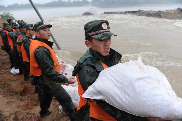 Soldiers repair the dyke breaches with sand bags along the Qingcao section of the Dasha River, in Tongcheng City, east China's Anhui Province, July 12, 2010. Tongcheng city was hit by a heavy rainstorm on July 11, causing dyke breaches on the Dasha River that threatened residents' safety. Nearly 300 soldiers rushed to the site to repair breaches. [Photo/Xinhua]