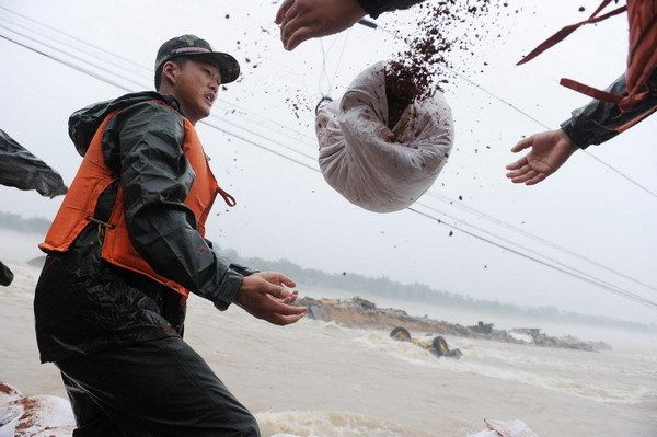 Soldiers repair the dyke breaches with sand bags along the Qingcao section of the Dasha River, in Tongcheng City, east China's Anhui Province, July 12, 2010. [Photo/Xinhua]