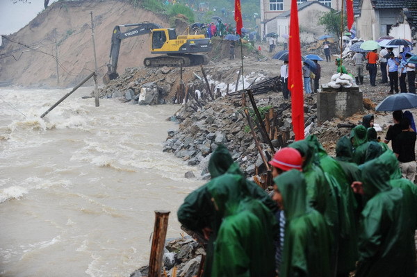 An excavator works at the breached dyke along the Qingcao section of the Dasha River, in Tongcheng City, east China's Anhui Province, July 12, 2010. [Photo/Xinhua]